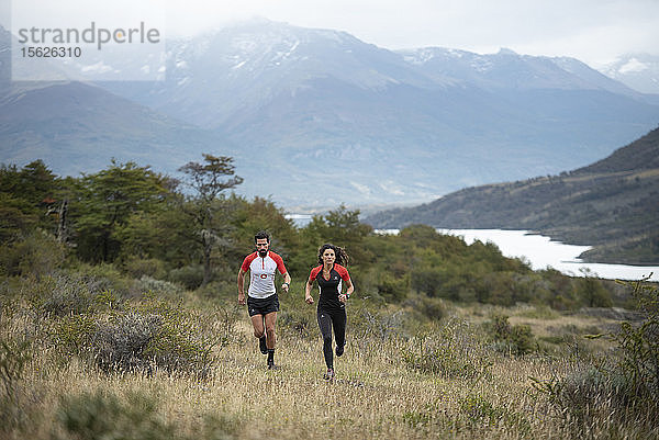 Frontansicht eines Mannes und einer Frau beim Trailrunning im Nationalpark Torres del Paine  Region Magallanes  Chile