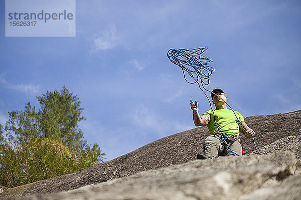 Kletterer wirft das Seil vor dem Abseilen von der Klippe herunter