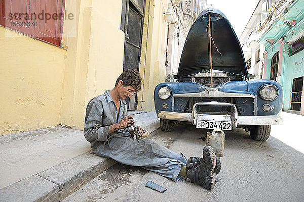 Mann repariert Auto auf der Straße in Havanna  Kuba