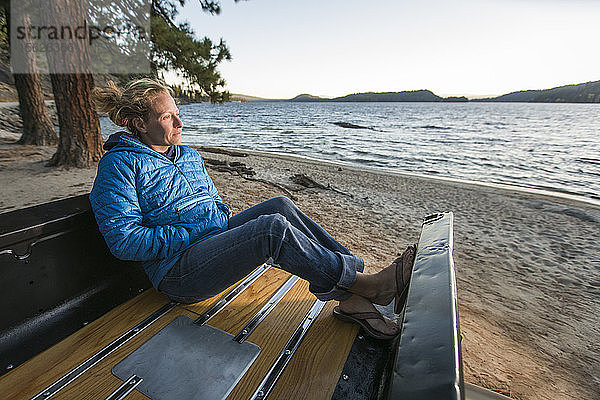 Frau sitzt in einem renovierten Truck und beobachtet den Sonnenuntergang am geschützten Strand des Payette Lake in McCall  Idaho  USA