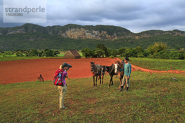 Amerikanerin fotografiert ihren Führer und ihre Pferde während eines Ausritts durch Tabakplantagen im Vinales-Tal im Westen Kubas