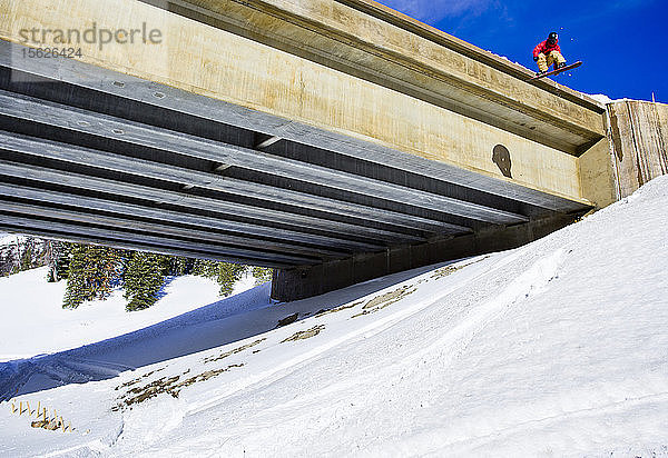 Ein Mann springt mit seinem Snowboard von einer Brücke am Togwotee Pass in Wyoming.