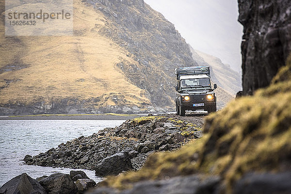 Frontansicht eines Geländewagens  der an der Küste entlang fährt  Färöer Inseln  Dänemark