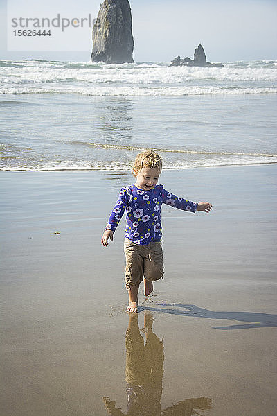 Ein kleines Mädchen rennt vor den Wellen des Ozeans am Cannon Beach  Oregon  davon.