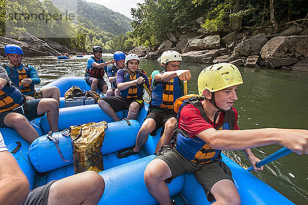 Pfadfinder des Pfeilordens paddeln auf einem Floß durch flaches Wasser in Richtung einer weiteren Stromschnelle auf dem New River  während eines Wildwasserabenteuers in der New River Gorge  in der Nähe von Fayetteville  außerhalb des Summit Bechtel Reserve (SBR)  WV. Die OA-Pfadfinder nehmen an einem Dienst- und Abenteuerprogramm im SBR teil. Pfadfinder auf der rechten Seite  von vorne nach hinten - Walter Sterling  Noah Lopez  Patrick Bonorden  Nick Dannenmiller und Floßführer. Auf der linken Seite - Keith Roscoe