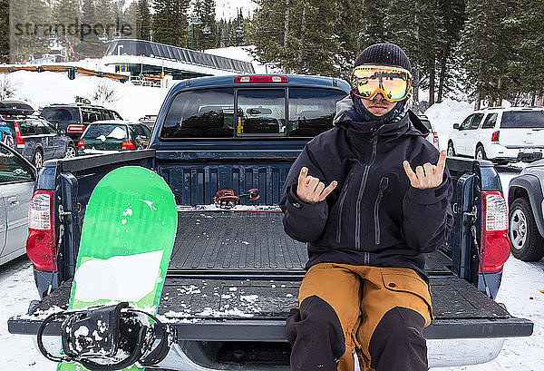 Porträt eines Snowboarders auf dem Rücksitz eines Pick-up-Trucks