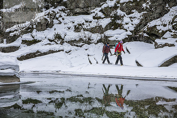 Zwei Männer gehen durch den Schnee und bereiten sich auf das Eisklettern vor.