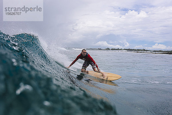 Große Wolken über einem männlichen Surfer auf einer Welle  Male  Malediven
