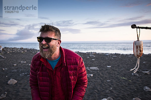 Mann lacht auf seinem Campingplatz in der Nähe des Ozeans an der verlorenen Küste