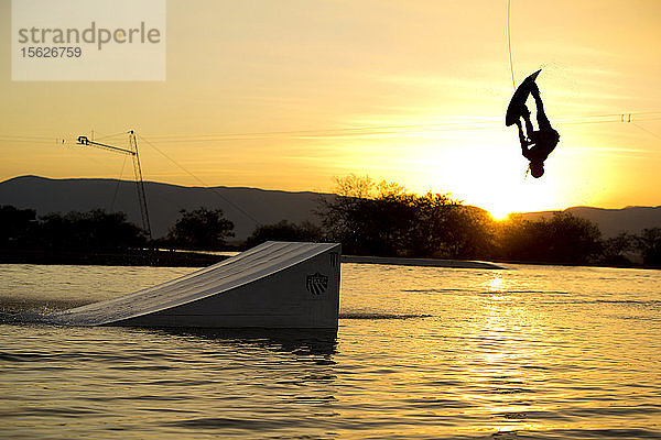 Silhouette eines Wakeboarders  der von der Rampe gegen die untergehende Sonne springt  Tequesquitengo  Morelos  Mexiko