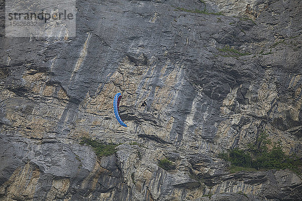 Eine nicht identifizierte Person macht Stunts mit einem Parawing vor einer riesigen Felswand. Lauterbrunnen  Schweiz.