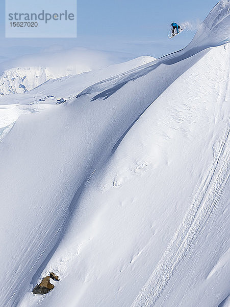 Snowboarder fängt Luft und schnappt sich ihr Brett beim Reiten einer Linie im Norden von British Columbia