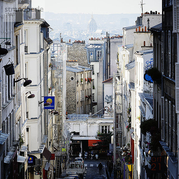 Vom einzigen Hügel von Paris blickt man durch eine enge Pariser Straße im Montmartre auf das Pariser Stadtbild hinunter.