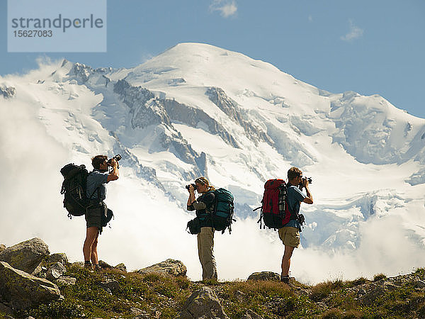 Drei Wanderer beim Fotografieren der französischen Alpen mit dem Mont Blanc im Hintergrund  Chamonix  Haute-Savoie  Frankreich