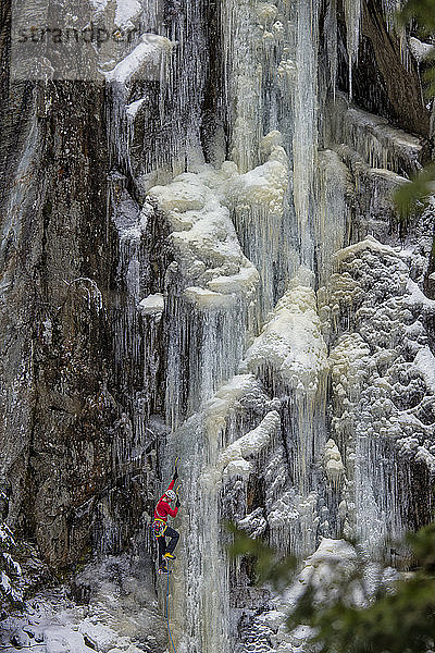 Ein Mann in einer roten Jacke klettert auf dem Eis.
