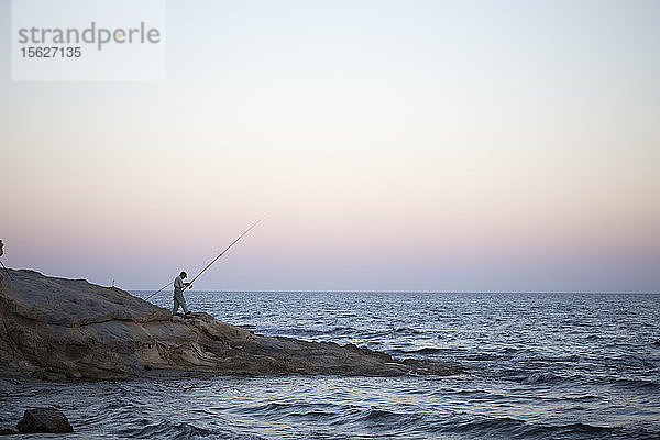 Ein Mann angelt bei Sonnenuntergang in Calpe  Alicante.