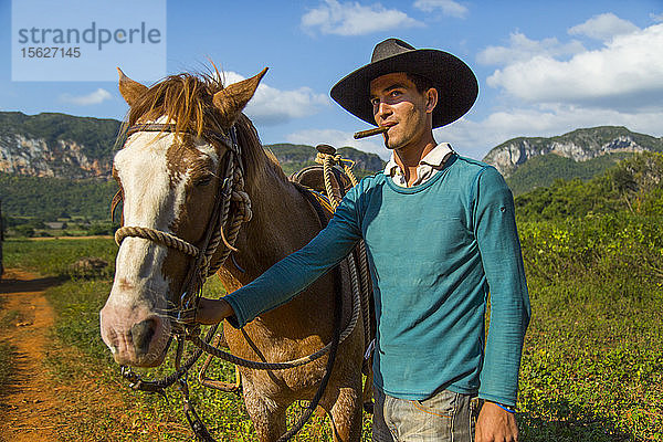 Kubanischer junger Mann mit einer Zigarre und seinem Pferd. Vinales  Kuba.