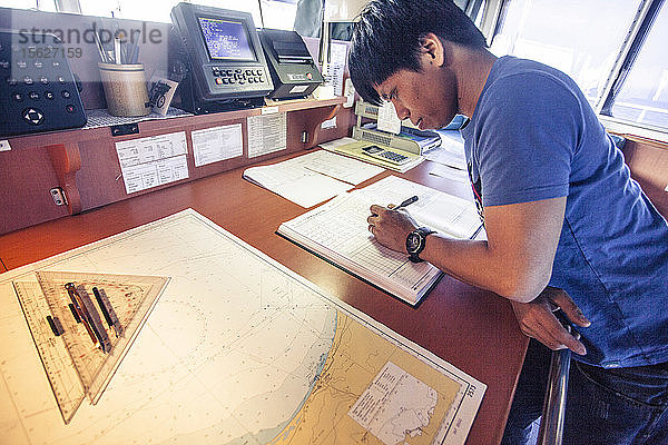 Ein Offizier auf einem Containerschiff prüft vor der Durchfahrt durch den Golf von Aden Karten und Pläne.