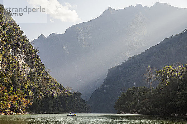 Robert Hahn betrachtet die über ihm aufragenden Karstfelsen am Nam Ou Fluss in der Nähe von Muang Ngoi  Laos.