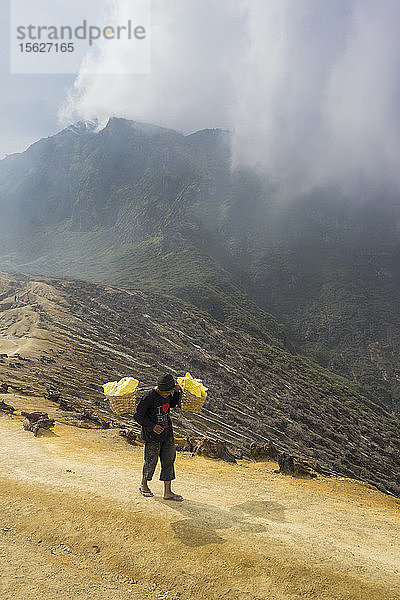 Bergleute wandern mit Schwefel aus dem Krater  Vulkan Kawah Ijen  Banyuwangi  Java  Indonesien