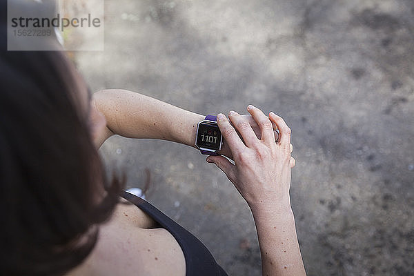 Eine Frau überprüft ihre Fit Bit Fitness-Tracker-Uhr am Handgelenk.