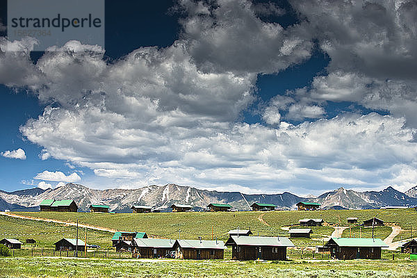 Holzhütten stehen auf einem Hügel mit Bergen im Hintergrund in Colorado.