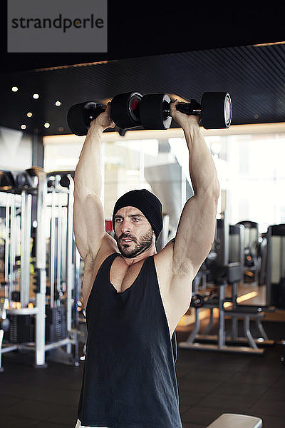 muskulöser Mann mit Krafttrainingsgeräten in einem Sportstudio