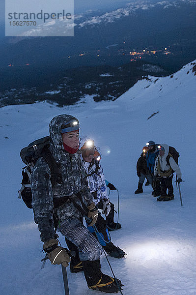 Jungen im Alter von 13 bis 17 Jahren von der Venturing Crew 191 aus Glendora  Kalifornien  setzen ein Jahr Training in die Praxis um  als sie versuchen  den Gipfel des Mount Shasta über die Avalanche Gulch-Route im Shasta Trinity National Forest in Nordkalifornien zu erreichen. Der Mount Shasta ist ein massiver  vergletscherter Vulkan und mit 14.179 Fuß der zweithöchste Gipfel in der Cascade Range und der fünfthöchste in Kalifornien; er ist mit keinem anderen Gipfel verbunden und erhebt sich abrupt 10.000 Fuß über das umliegende Gelände. Die Pfadfinder der Venturing Crew 191 (Venturing Crews sind ein Zweig der Pfadfinder  der sich auf abenteuerliche Aktivitäten konzentriert) hatten sich ein Jahr lang auf die Besteigung des Mount Shasta vorbereitet. Dies war ihre erste Erfahrung mit dem Klettern in steilem Schnee  und sie wurden bei der Besteigung von Führern der SWS Mountain Guides unterstützt. Frühmorgens vor Sonnenaufgang klettern Josh Kolbach und Jeremy Kolbach mit Steigeisen und Eispickeln als Seilschaft  darunter ein weiteres Team  bestehend aus den Bergführern Casey Hurden (vorne)  Morgan Howlett  Dillon Travis und Mark Howlett  im steilsten Teil der Avalanche Gulch auf etwa 11.500 Fuß  auf dem Weg zum Gipfel des Mount Shasta  Shasta Trinity National Forest  Kalifornien. Die Crew begann ihren Aufstieg sehr früh  um sicherzustellen  dass sie den Gipfel noch vor dem Mittag erreichten und die Lichter der Stadt Mount Shasta im Tal darunter zu sehen sind.
