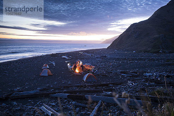 Zwei Freunde genießen das Lagerfeuer am Meer an der Lost Coast