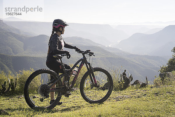 Seitenansicht einer Frau mit Mountainbike in natürlicher Umgebung mit Bergen im Hintergrund  Pena del Aire  Huasca de Ocampo  Hidalgo  Mexiko