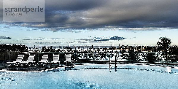 Weitwinkelansicht eines Swimmingpools und eines wolkenverhangenen Horizonts.