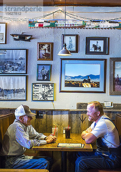 Seitenansicht von zwei reifen Männern  die in einem Restaurant am Tisch sitzen  Paisley  Oregon  USA