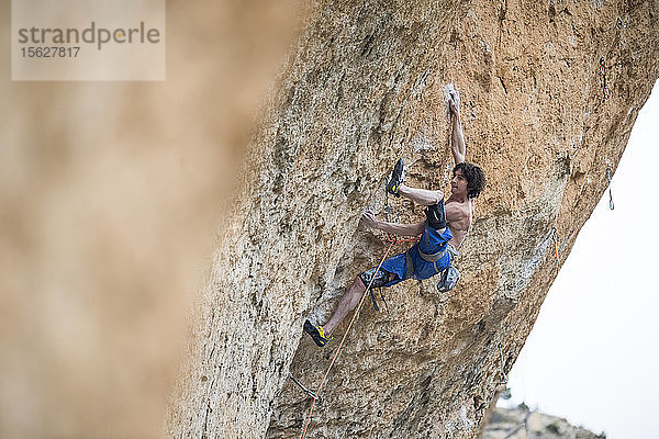 Seitenansicht eines einzelnen Bergsteigers ohne Hemd  der an einem schwierigen Felsen klettert  Siurana  Katalonien  Spanien