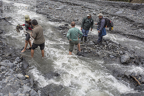 Foto von fünf Wanderern bei der Flussüberquerung im peruanischen Nebelwald