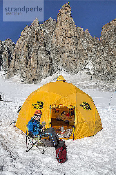 Frau ruht sich nach einer Gipfelbesteigung im Tal von Chamonix auf einem Campingstuhl in der Nähe des Zeltes aus