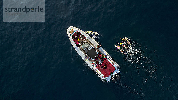 Eine Luftaufnahme eines Motorbootes im Mittelmeer mit drei Schwimmerinnen