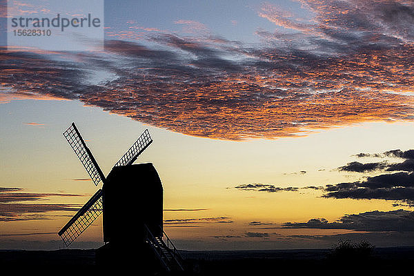 Windmühle bei Sonnenuntergang unter einem romantischen Wolkenhimmel.