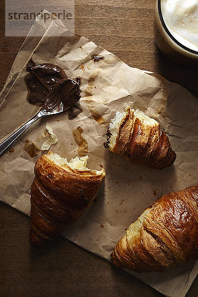 Zwei Croissants auf brauner Papiertüte mit Nusscreme und Kaffee