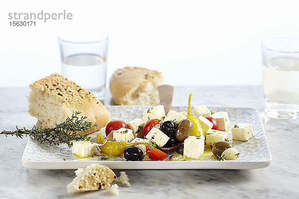 In Olivenöl eingelegter Feta mit Tomaten  Knoblauch  Peperoni und Oliven  dazu Sesam-Fladenbrot