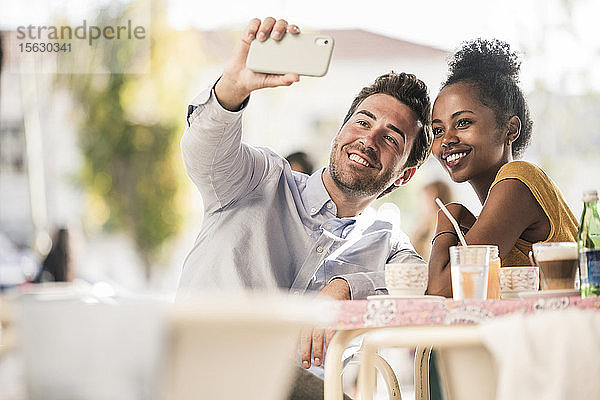 Glückliches junges Paar beim Selfie in einem Straßencafé