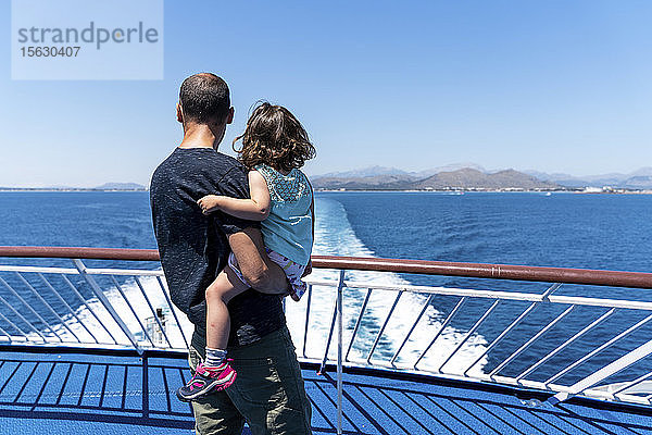 Rückansicht eines Vaters und einer kleinen Tochter zusammen auf dem Deck eines Schiffes mit Blick in die Ferne  Mallorca  Spanien