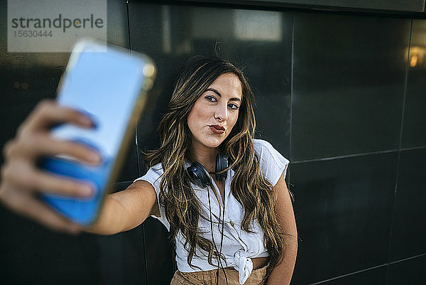 Junge Frau  die mit ihrem Smartphone einen Selfie macht und schmollt