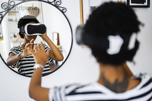 Junge Frau mit VR-Brille vor dem Spiegel zu Hause