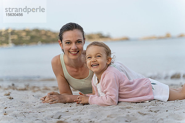 Porträt einer glücklichen Mutter mit Tochter am Strand