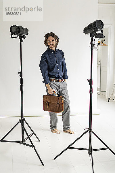 Porträt eines Fotografen  der in seinem Atelier eine Tasche hält