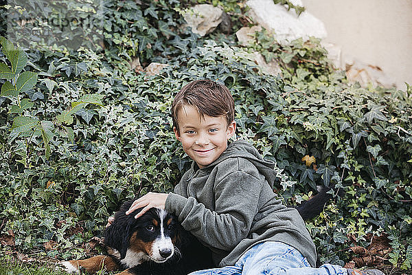 Junge spielt mit seinem Berner Sennenhund im Garten