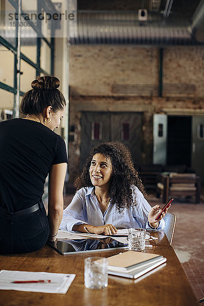 Zwei junge Geschäftsfrauen mit Smartphone im Loft-Büro