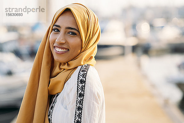Junge muslimische Frau mit gelbem Hidschab beim Spaziergang am Hafen