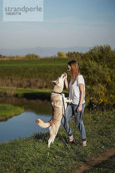 Junge Frau unterrichtet ihren Hund in der Natur