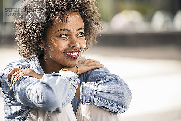 Porträt einer lächelnden jungen Frau  die sich im Freien entspannt